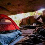 Explore the serenity of cave camping with a red tent in a natural setting, capturing relaxation and adventure.